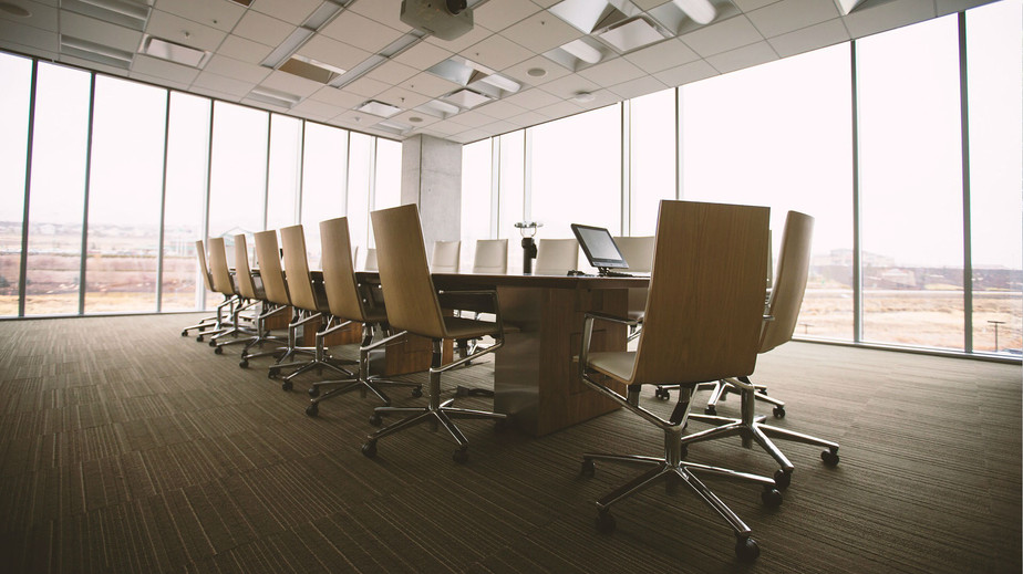 Conference room featuring chairs arranged around a table with a laptop positioned at the center.