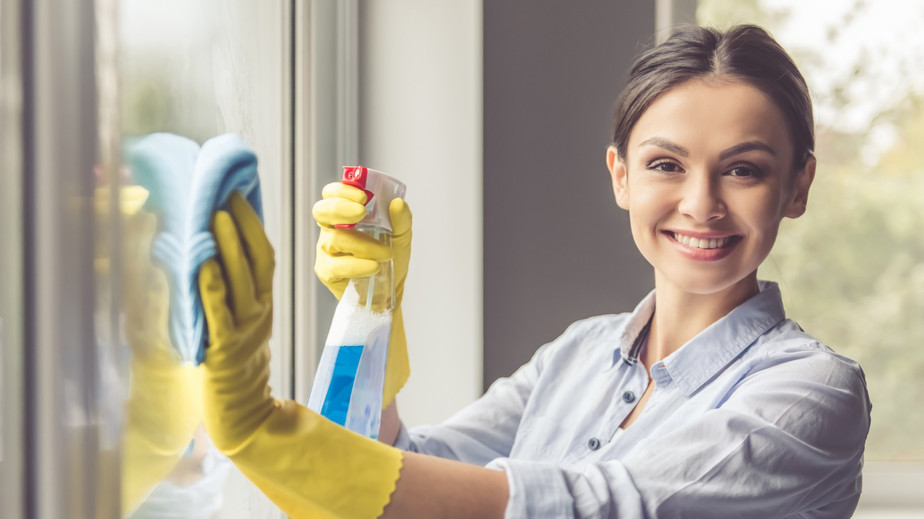 A woman in rubber gloves cleans a window, showcasing her dedication to maintaining a spotless home environment.